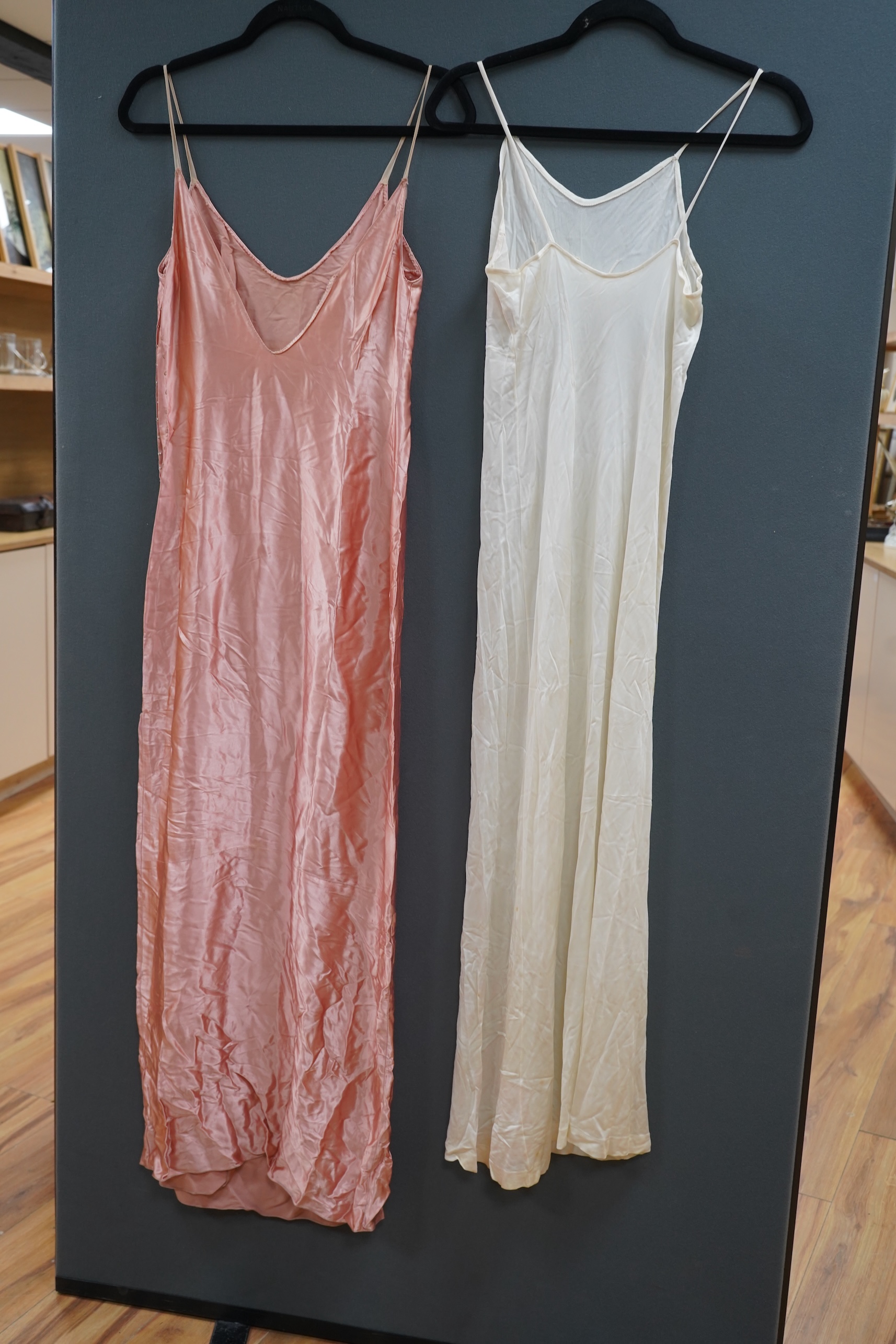 Two late 19th early 20th century long baby night gowns and two shorter baby gowns, together with a pink satin ladies full length slip and a similar cream silk stockinette slip, the bodices worked on baby dresses are embr